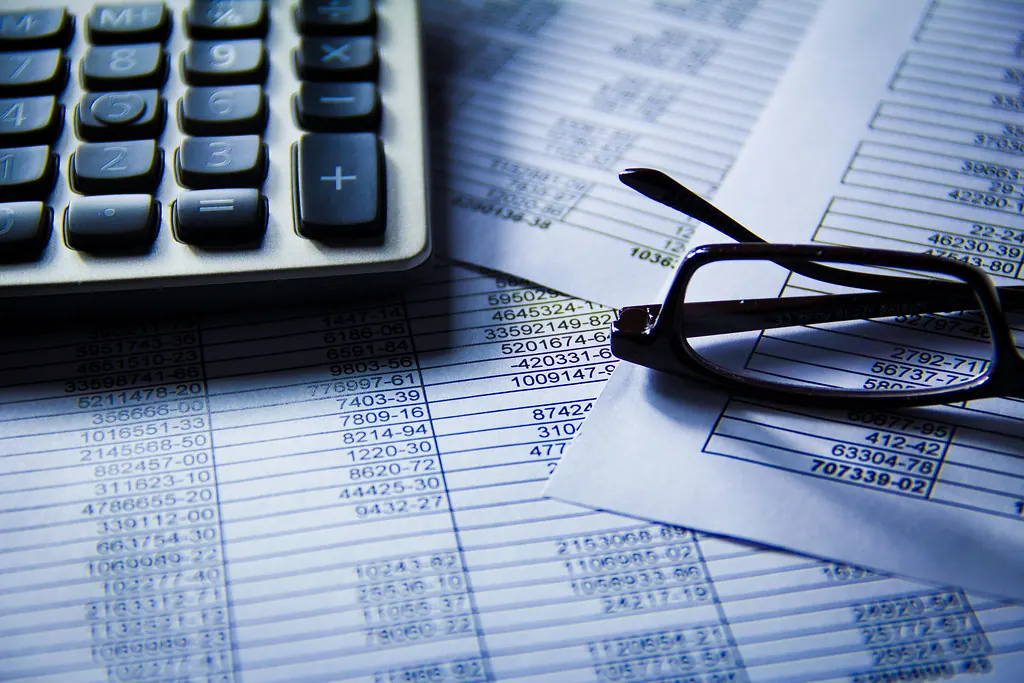 Calculadora y gafas sobre hojas con cifras financieras