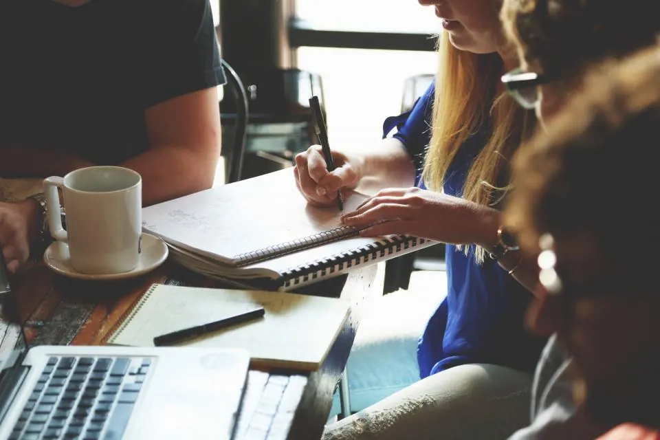 Equipo de trabajo reunido alrededor de una mesa con cuadernos y portátil
